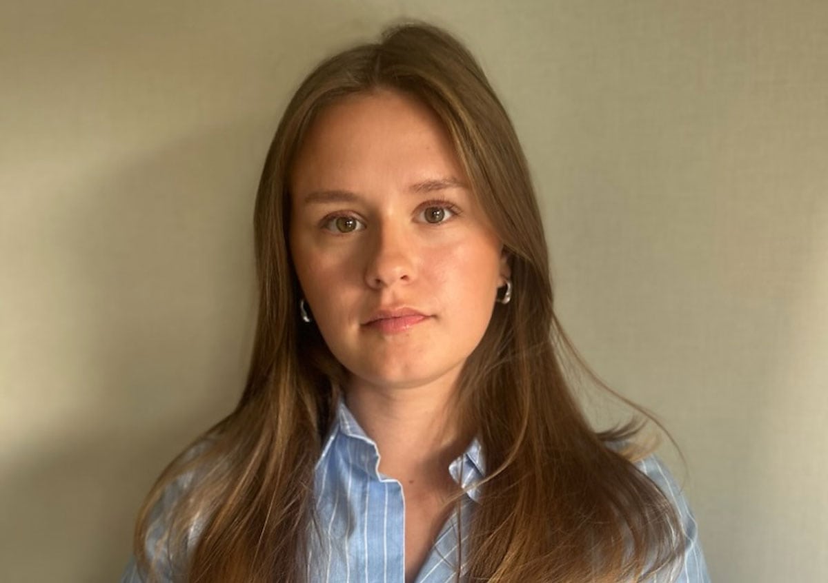Emma Wellhardh i blåvitrandig skjorta, fotograferad framifrån mot en ljus, neutral bakgrund.